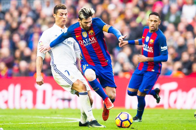 FC Barcelona's Lionel Messi wins the ball past Real Madrid's Cristiano Ronaldo as Neymar (in background) watches, during their El Clasico La Liga match at Camp Nou, last December