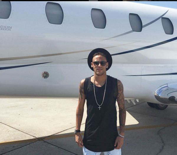 Brazil and FC Barcelona forward Neymar poses next to his privately owned jet