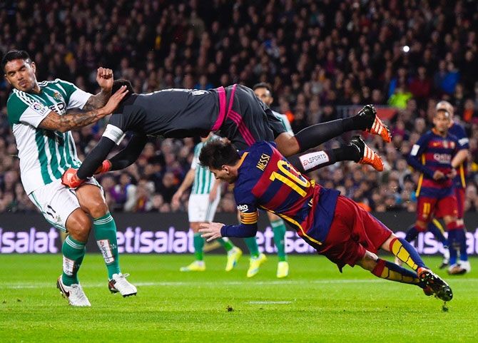 FC Barcelona's Lionel Messi and Real Betis's Adan, centre, clash during their La Liga match on Wednesday