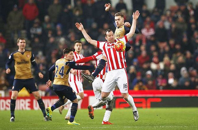 Arsenal's Calum Chambers and Stoke's Charlie Adam vie for possession during an aeriel duel