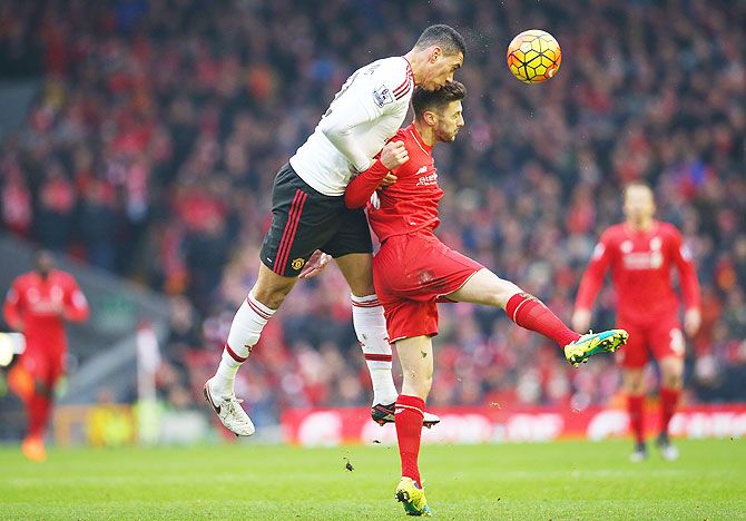 Manchester United's Chris Smalling wins a header as he duels with Liverpool's Adam Lallana