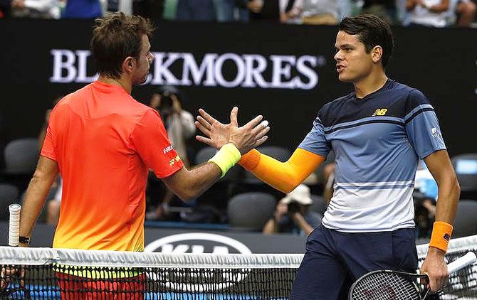 Milos Raonic (right) greets Stan Wawrinka at the net after winning their fourth round match