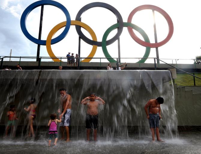  People cool off beneath a water fountain beneath the Olympic rings in Madureira Park in Rio de Janeiro