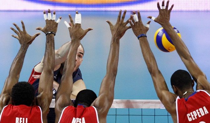 Clayton Stanley (rear) of the US spikes the ball against Yenry Bell, Isbel Mesa, centre, and Rolando Cepeda, right, of Cuba during their FIVB World League semi-finals men's volleyball match