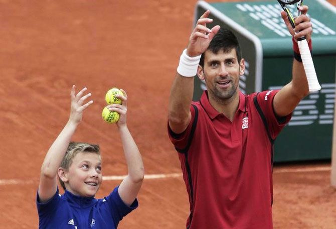 Novak Djokovic celebrates with a ball boy after his victory over Tomas Berdych on Thursday