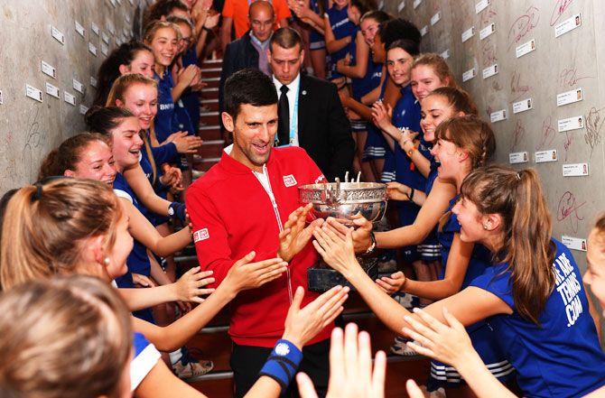 New French Open champion Novak Djokovic celebrates with the ball girls following his victory at Roland Garros on Sunday