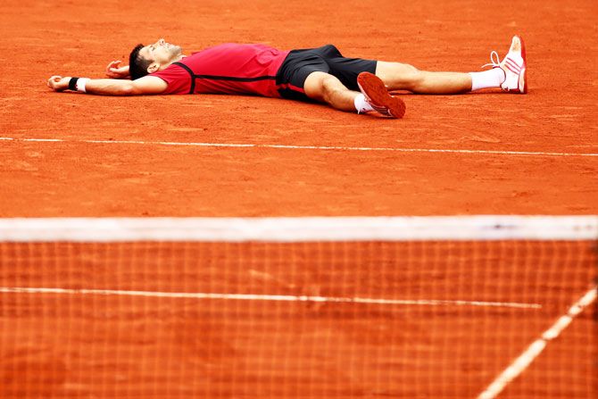 Novak Djokovic lies on the ground as he celebrates his French Open win on Sunday