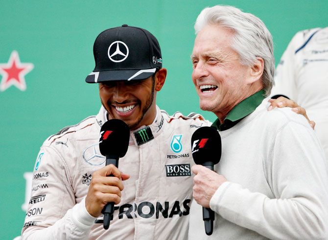Lewis Hamilton celebrates his win on the podium with actor Michael Douglas