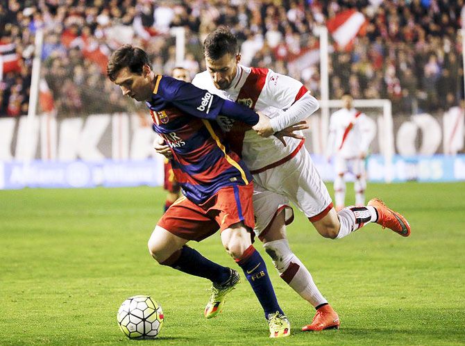 Barcelona's Lionel Messi is challenged by Rayo Vallecano's Roberto "Tito" Roman as they vie for possession