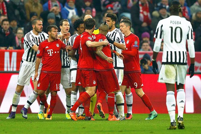 Bayern Munich's Arturo Vidal and Juventus' Juan Cuadrado are restrained by teammates as they argue