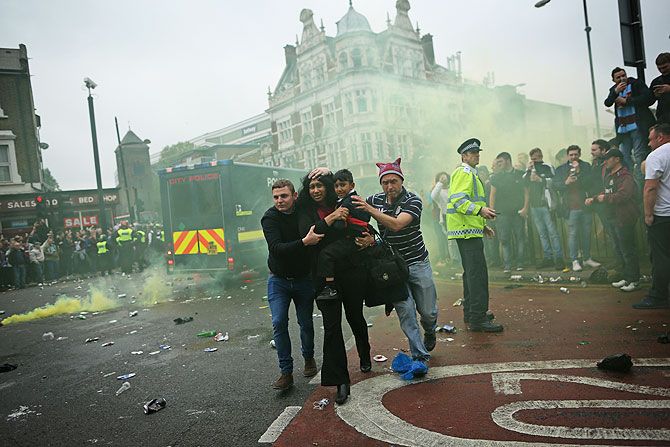A woman and a child are helped past West Ham fans as people become violent and start throwing bottles at police outside the Boleyn Ground on Tuesday
