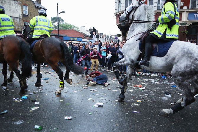 A man is knocked over by police horses as West Ham fans become violent and start throwing bottles at police outside the Boleyn Ground