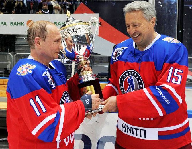 Russian President Vladimir Putin and Soviet former player Alexander Yakushev hold a trophy as they take part in a gala game of the Night Ice Hockey League on Tuesday