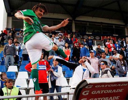 Chilean club Audax Italiano's Sebastian Pol takes a swipe as he kicks a rival team's supporter at Universidad Catolica's Carlos de Apoquindo stadium on Saturday