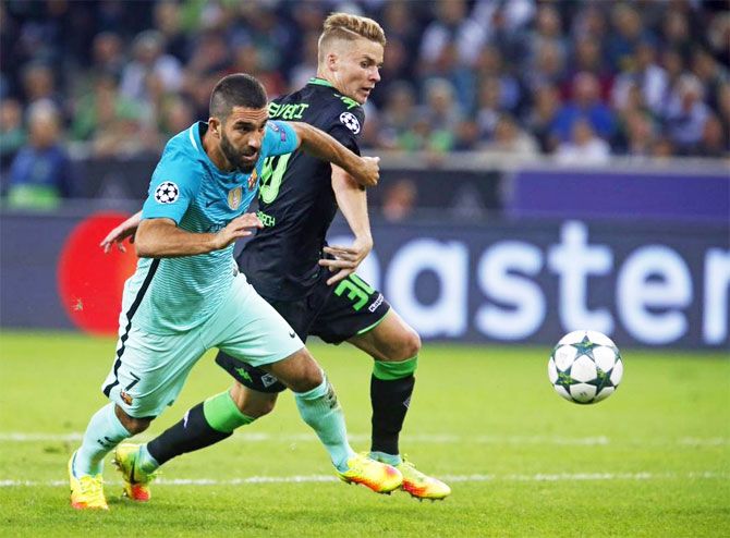 FC's Barcelona's Arda Turan runs past a Borussia Moenchengladbach player as they vie for possession