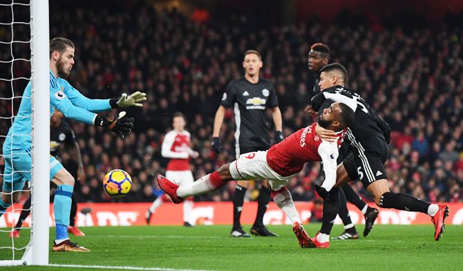  Arsenal's Alexandre Lacazette attempts to shoot as he is challenged by Manchester United's Marcos Rojo and denied by keeper David de Gea