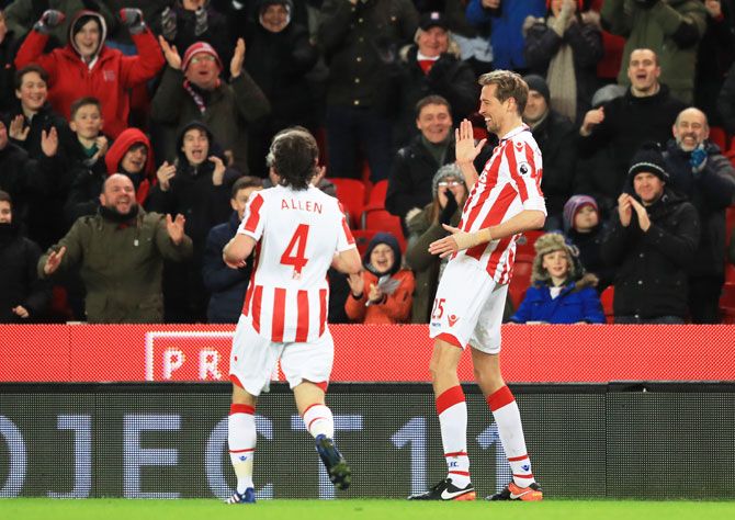 Stoke City's Peter Crouch (right) celebrates in his standard break dance style after scoring the opening goal against Everton, his 100th EPL goal, at Bet365 Stadium in Stoke on Trent, England, on Wednesday