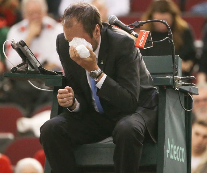 Chair umpire Arnaud Gabas reacts to getting hit in the eye with a ball hit by Denis Shapovalov of Canada
