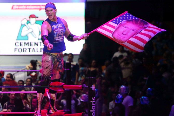 US wrestler Sam Adonis, 27, role-playing as a fan of US President Donald Trump, waves a flag with Trump's face during a wrestling fight at the Coliseo Arena in Mexico City, Mexico, on Sunday