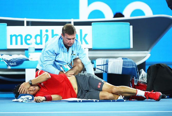 Kei Nishikori receives treatment from the physio during an injury time out in his fourth round match against Roger Federer