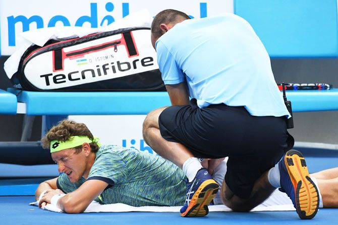 Denis Istomin receives medical attention in his fourth round match against Grigor Dimitrov