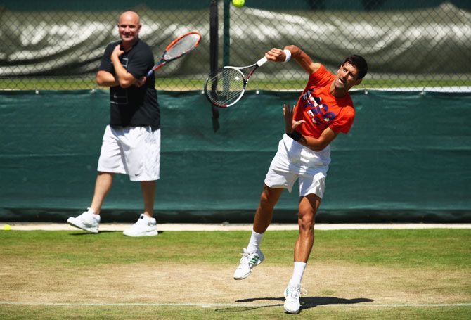 Serbia's Novak Djokovic is watched by his coach Andre Agassi during practice at Wimbledon