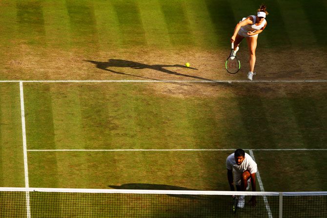 Canada's Gabriela Dabrowski serves as she partners India's Rohan Bopanna during their mixed-doubles quarter-final against Great Britain's Heather Watson and Finland's Henri Kontinen at the Wimbledon Lawn Tennis Championships at the All England Lawn Tennis and Croquet Club at Wimbledon in London, on Thursday