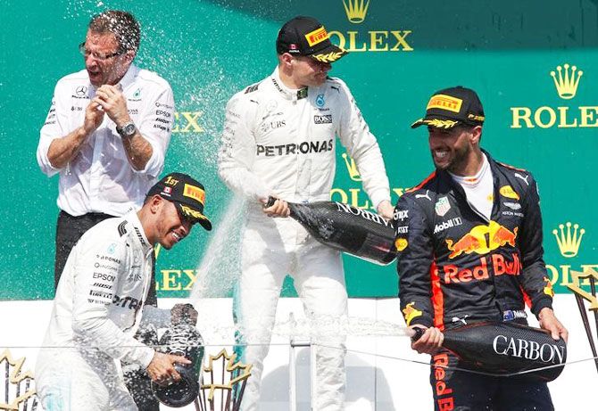 Podium finishers Mercedes’ Lewis Hamilton (bottom left), teammate Valtteri Bottas (centre) and Red Bull's Daniel Ricciardo (right) celebrate after the race