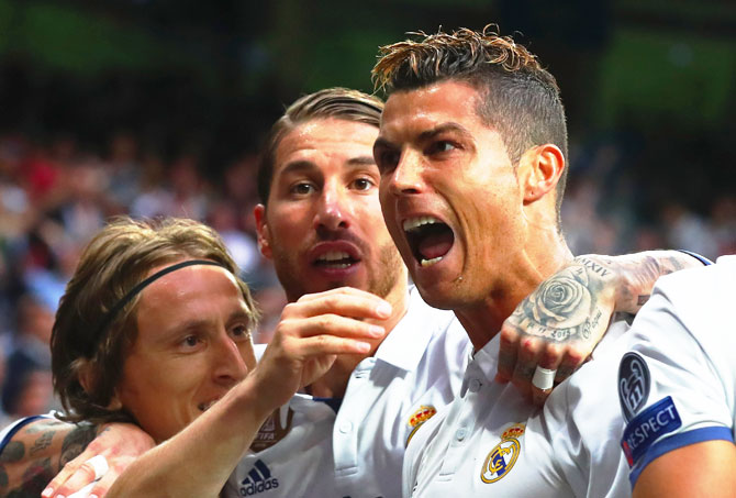 Real Madrid's Cristiano Ronaldo celebrates as he scores their first goal with teammates Luka Modric and Sergio Ramos during their UEFA Champions League sem-final first leg match against Club Atletico de Madrid at Estadio Santiago Bernabeu in Madrid on Tuesday