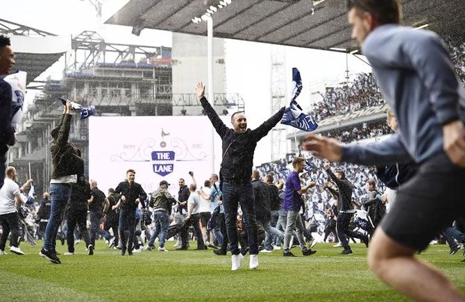 Fans of Tottenham Hotspur invade the pitch after the team's 2-1 win over Manchester United in White Hart Lane's final match on Sunday