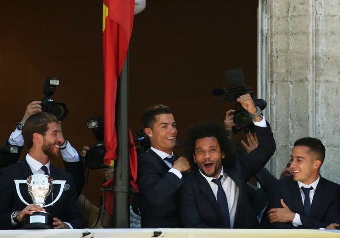 (Left-Right) Real Madrid's Sergio Ramos, Cristiano Ronaldo, Marcelo and Lucas Vazquez celebrate on a balcony at the headquarters of Madrid's regional government, the Autonomous Community of Madrid, in Madrid, Spain, on Monday