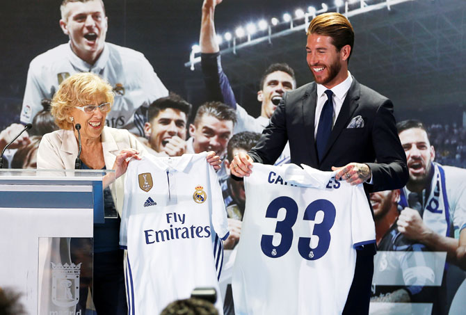 Real Madrid's Sergio Ramos presents Madrid Mayor Manuela Carmena with a Real Madrid jerseys during a ceremony at the Town Hall in Madrid, on Monday