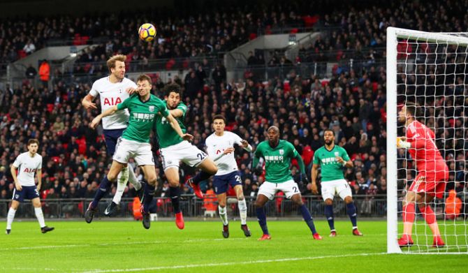 Tottenham's Harry Kane heads at goal as he is involved in an aerial challenge with West Bromwich Albion’s Ahmed Hegazi and Jonny Evans