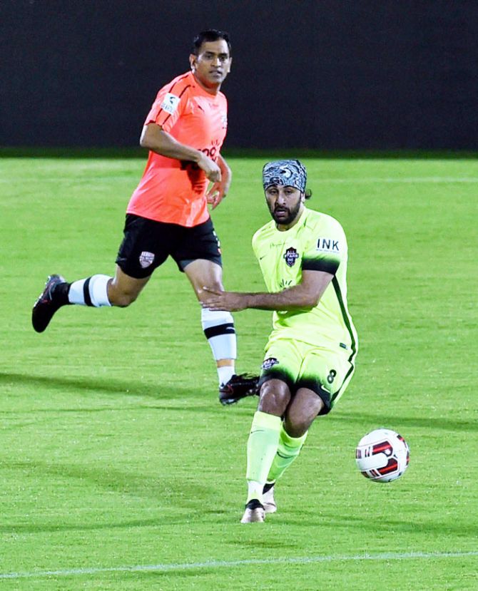Cricketer Mahendra Singh Dhoni watches as actor Ranbir Kapoor tries to control the ball during their Charity Football match in Mumbai on Sunday