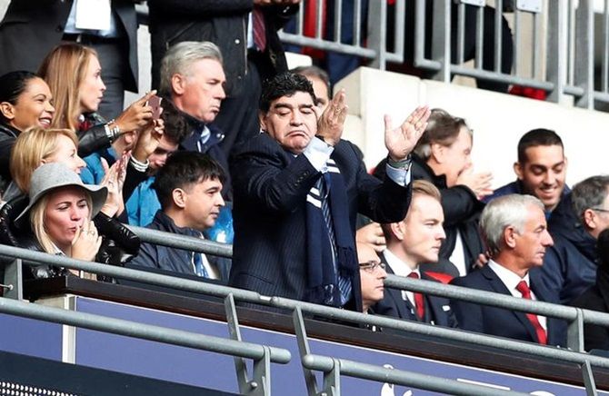 Argentina's football icon Diego Maradona applauds after Harry Kane scores Tottenham's first goal against Liverpool. 