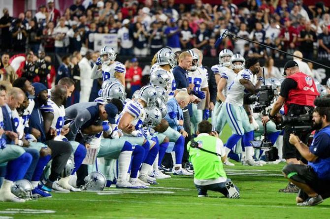 The Dallas Cowboys players, coaches staff and owner Jerry Jones take a knee prior to the National Anthem before the game against the Arizona Cardinals at University of Phoenix Stadium on Monday