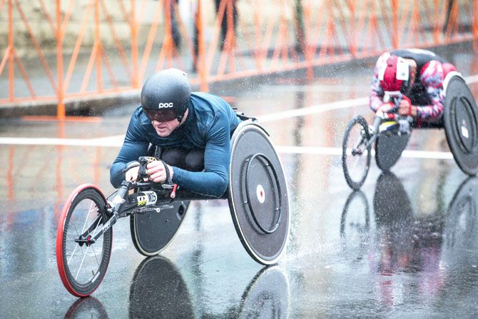 Wheelchair racers spray rain from their wheels as they make their way towards the 24th mile of the 2018 Boston Marathon on Monday