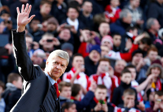 Arsenal manager Arsene Wenger waves as he walks onto the pitch before an English Premier League match against Stoke City at Britannia stadium in Stoke-on-Trent, central England on March 1, 2014