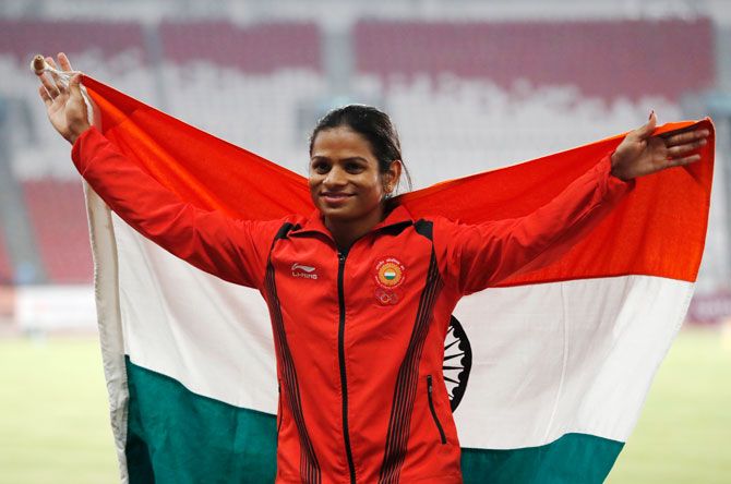 India's Dutee Chand of India poses with the national flag after completing her race to win the 100m silver medal at the Asian Games on Sunday