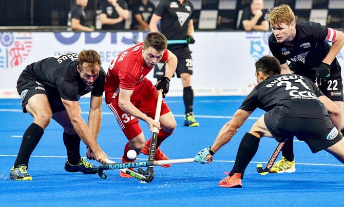 England's Zachary Wallace (red) is challenged by New Zealand players during their Men's Hockey World Cup match in Bhubaneswar on Monday