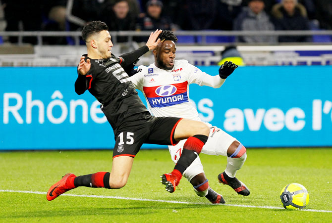 Lyon's Maxwel Cornet and Stade Rennes’ Ramy Bensebaini vie for possession