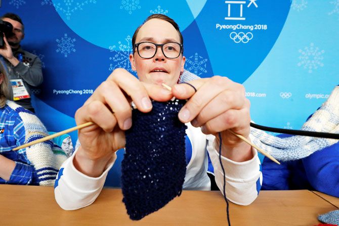 Antti Koskinen, snowboard head coach, shows how he knits, during a news conference in Pyeongchang on Tuesday