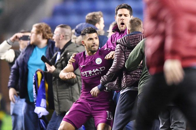 Sergio Aguero is restrained by a teammate as he reacts to teasing fans as while leaving the pitch after the match