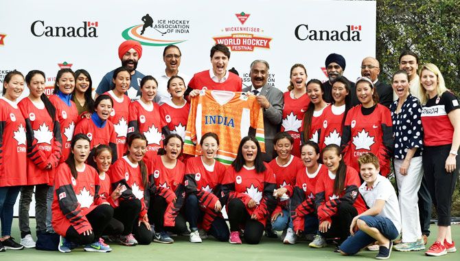 Canadian Prime Minister Justin Trudeau displays the Indian jersey as he poses for a photo with Indian women's ice hockey team in New Delhi on Saturday