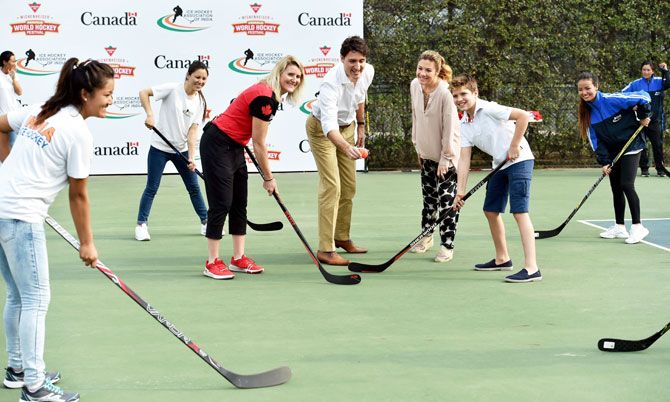 Canadian Prime Minister Justin Trudeau, First Lady Sophie Gregoire Trudeau, their son Xavier and Canadian ice hockey player Hayley Wickenheiser pose with ice hockey sticks along with members of the Indian women's ice hockey team in New Delhi on Saturday