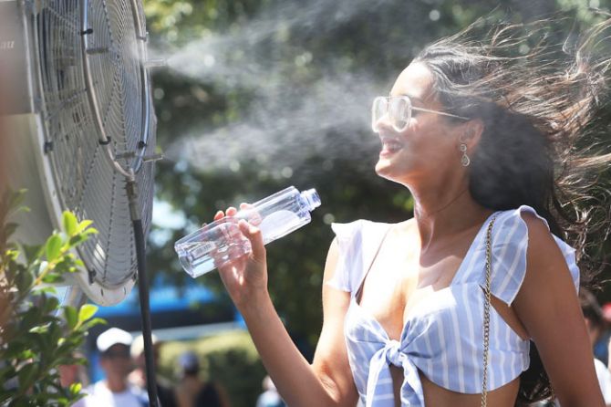 A spectator cools down in front of a misting fan at Melbourne Park