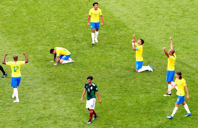 Mexico's Carlos Vela walks off dejected as Brazil's Thiago Silva, Marquinhos and teammates celebrate victory after the match