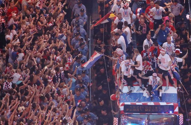 Croatia team players atop a bus celebrate with fans during the parade