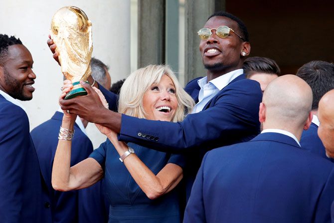 Brigitte Macron, the wife of French President Emmanuel Macron, and player Paul Pogba hold the trophy aloft