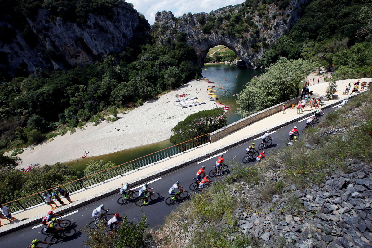 The peloton passes Vallon-Pont-d'Arc during the 188-km Stage 14 from Saint-Paul-Trois-Chateaux to Mende on July 21